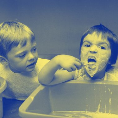 two kids with toothpaste all over their faces near a sink